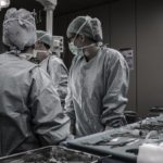 A group of surgeons huddled around their chief in the operating room